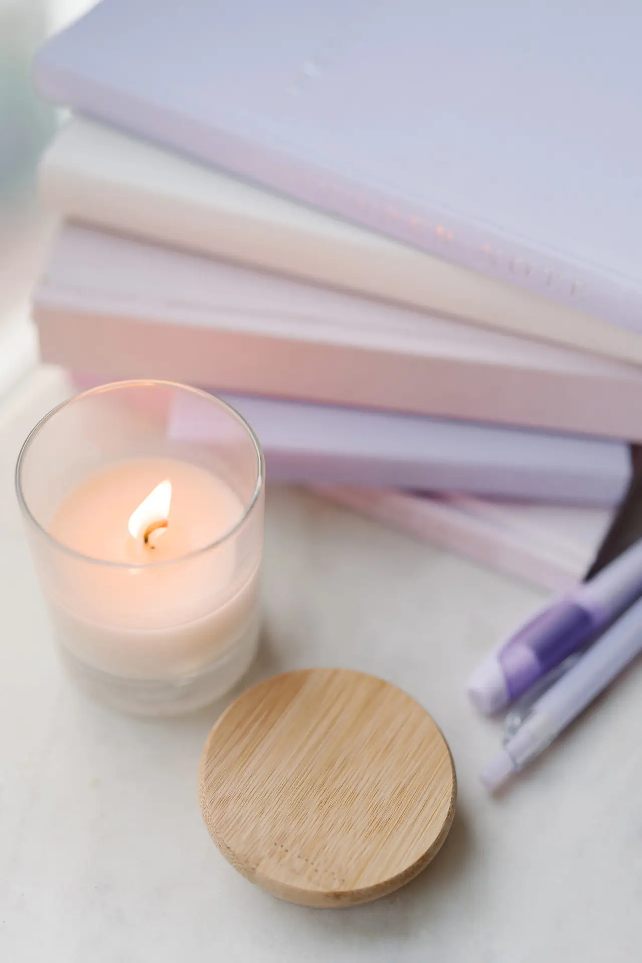 Burning candle on a desk next to books